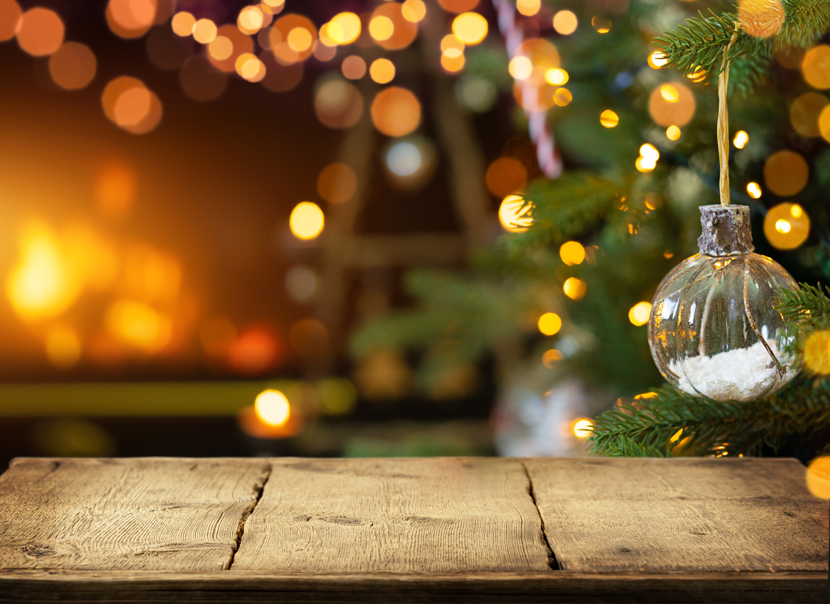 Empty wooden table on Christmas ornaments background with fireplace. Copy space.