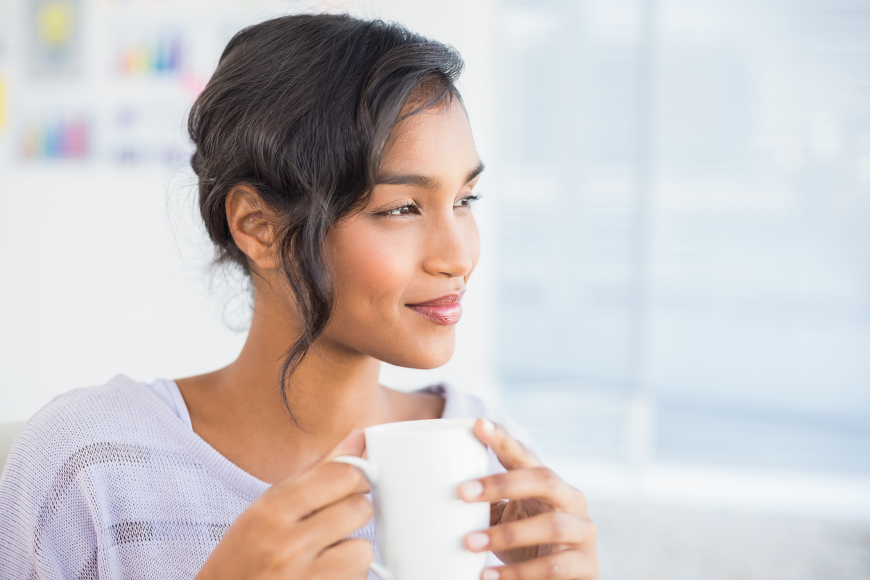 Casual businesswoman having a coffee at desk