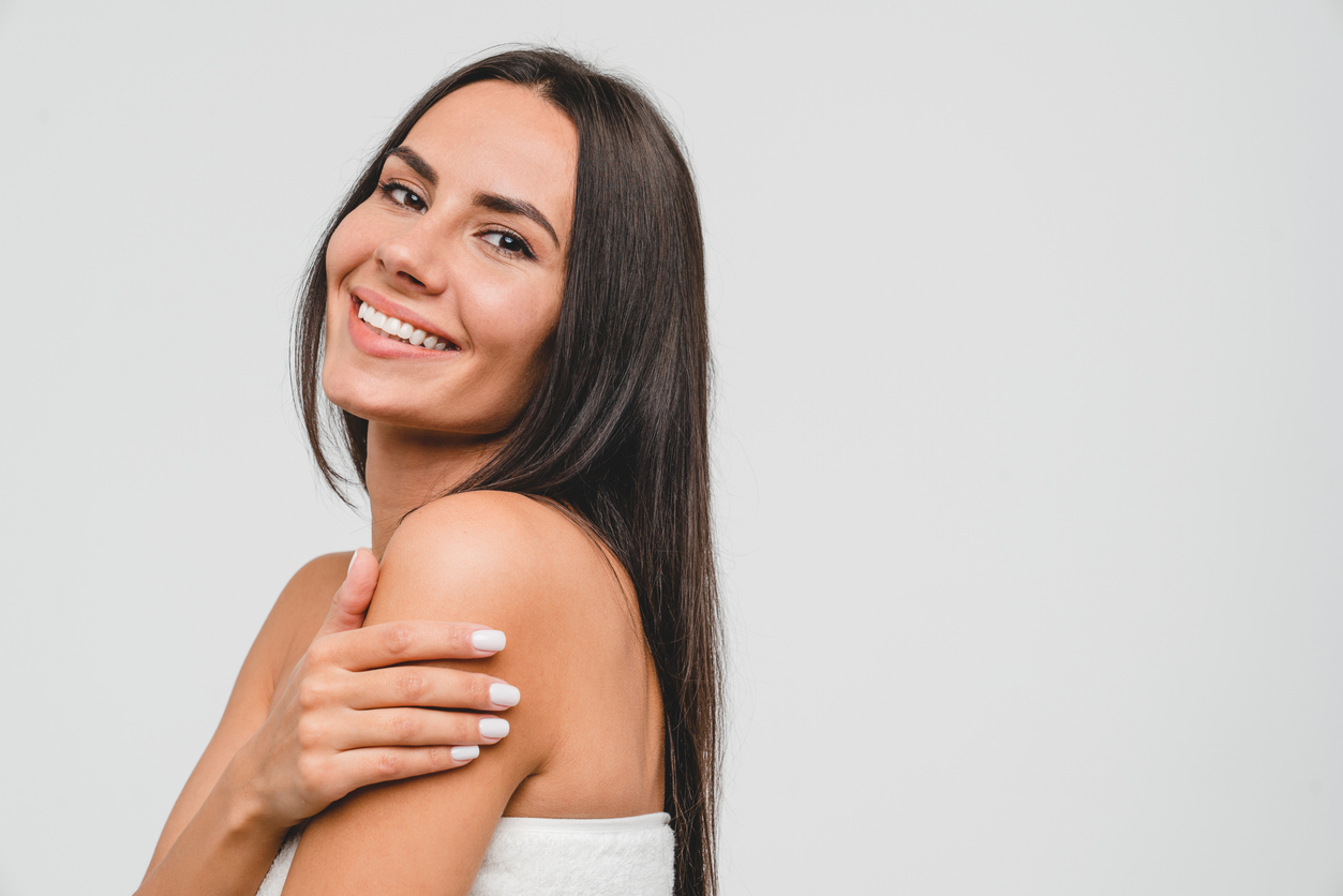 Happy healthy beautiful caucasian young woman in spa bath towel hugging embracing herself looking at camera isolated in white background. Beauty treatment and care