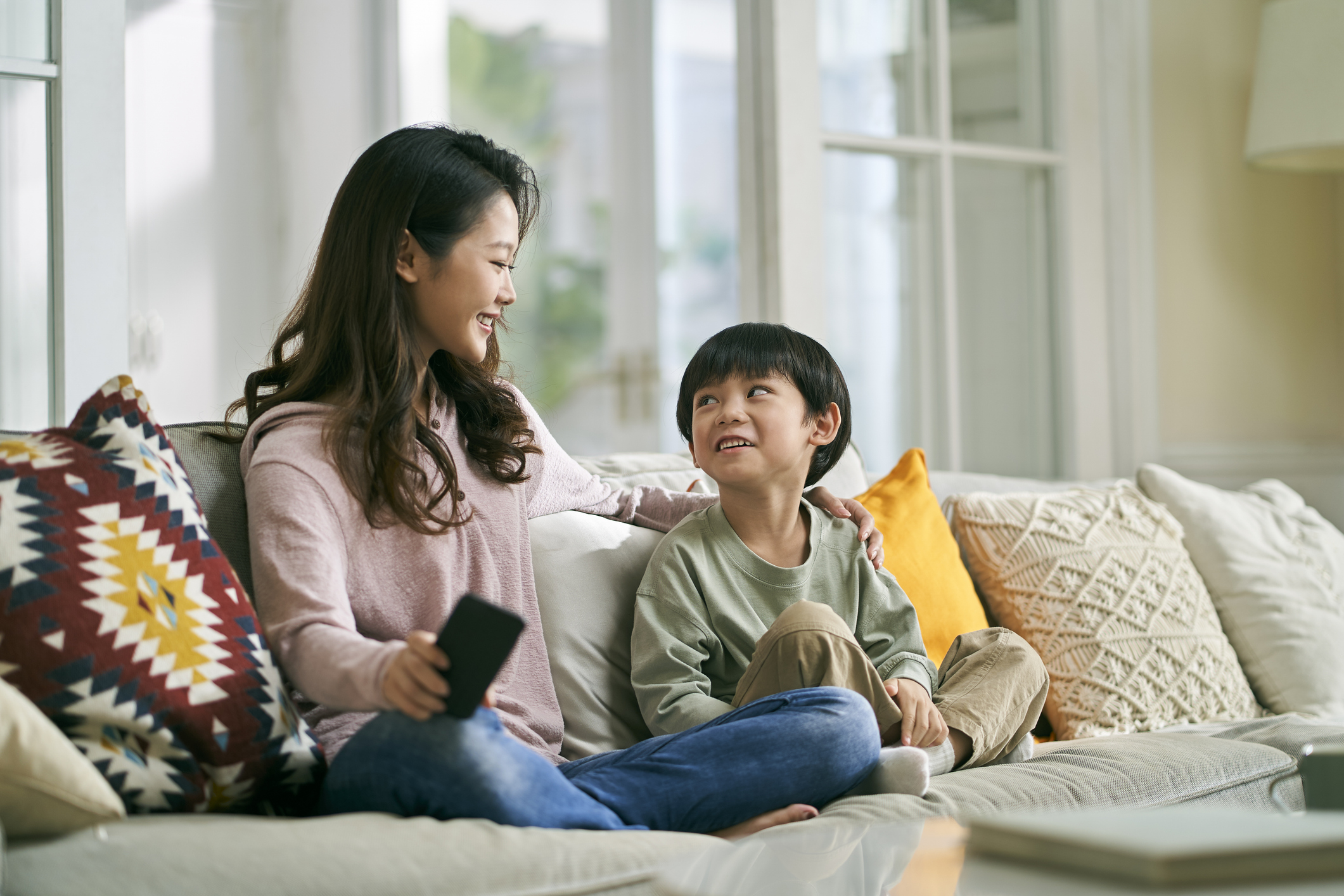 asian mother and son sitting chatting on couch at home