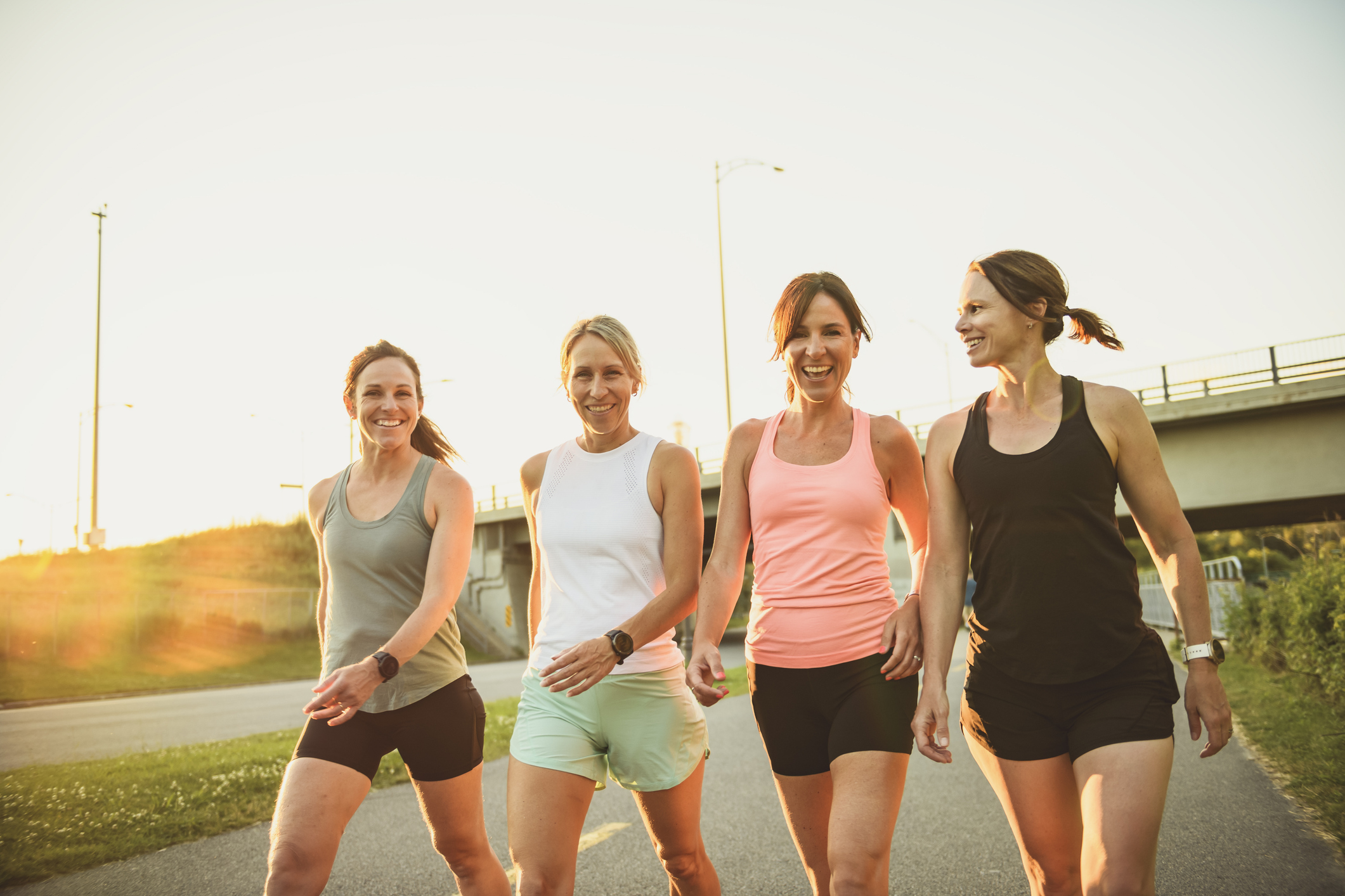 females in sportswear walking together bright sunny park in summer