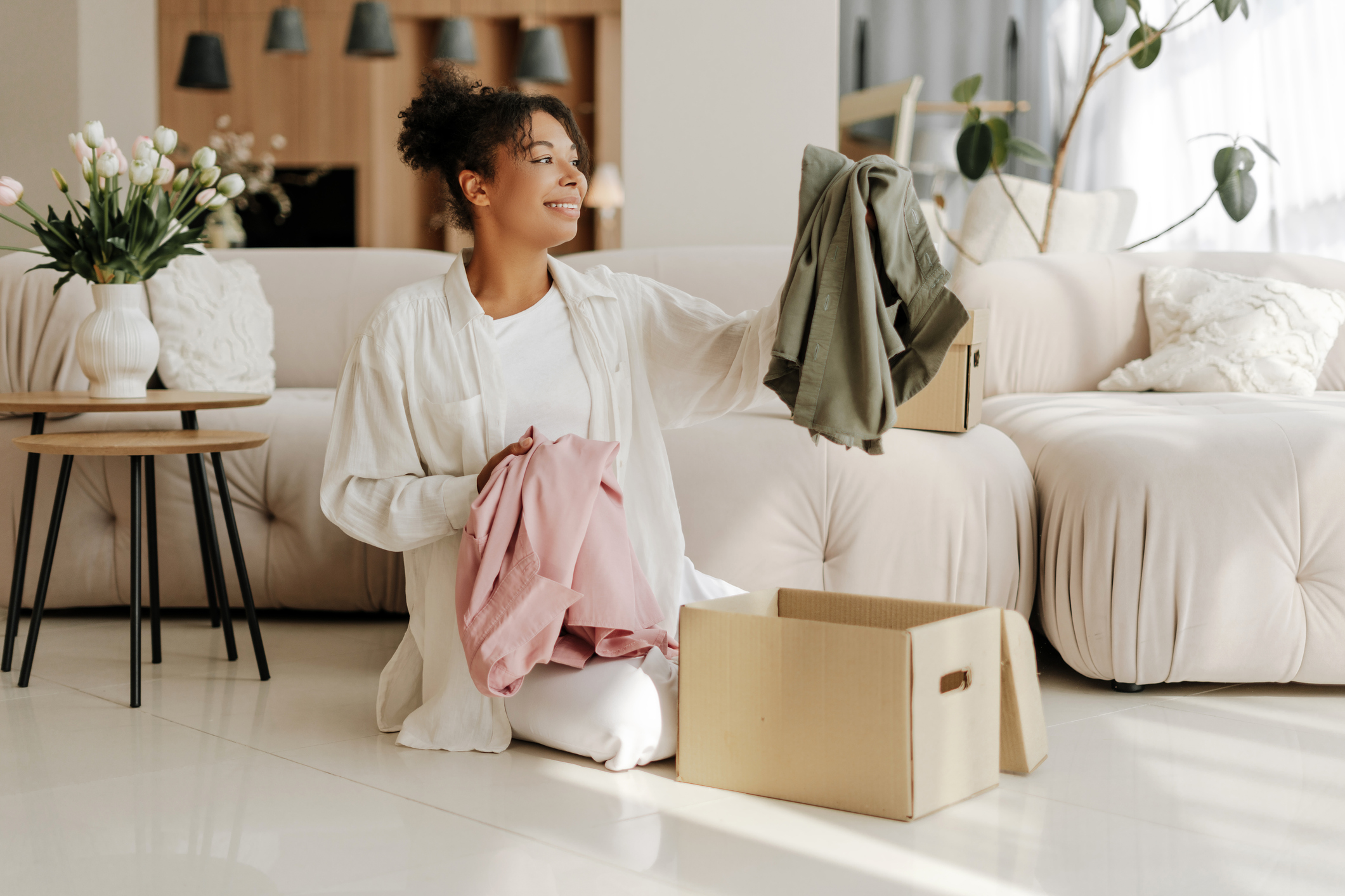 Young woman organizing clothes in cardboard boxes at home Young woman organizing clothes in cardboard boxes at home